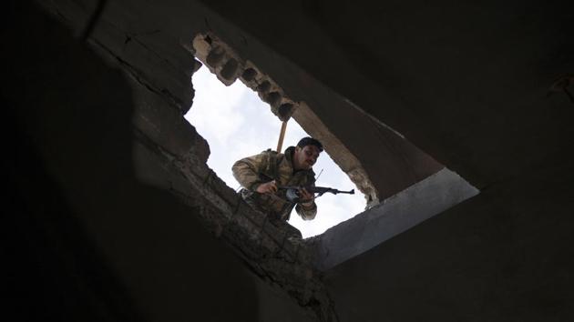 An SDF fighter enters a building as fight against Islamic State militants continues. Villages leading to Baghouz lie mostly empty and destroyed, ghost towns where the only sign of life is wild grass that grew after weeks of rare heavy rain. (Felipe Dana / AP)