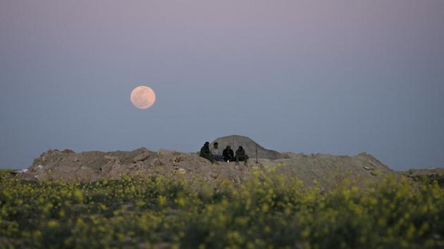 The moon rises behind SDF fighters at a defence post in the desert near the last land still held by Islamic State militants outside Baghouz. Over 30,000 people who left the last IS-held areas have arrived at the al-Hol camp in Syria’s northern Hassakeh province in the last few weeks, raising the overall population of the camp to almost 42,000. (Felipe Dana / AP)