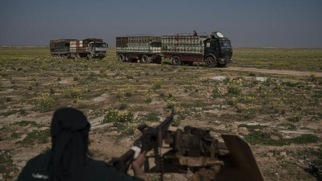 An SDF fighter watches as a convoy evacuating hundreds of men, women and children drives out of the last territory held by Islamic State militants in Baghouz. (Felipe Dana / AP)