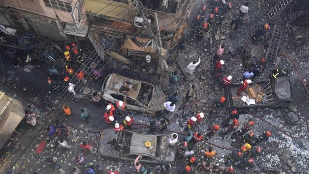 Rescuers stand at the site of the fire. The fire started in one building where chemicals for deodorants and other household uses were illegally stored and spread at lightning speed to four nearby buildings. (Mahmud Hossain Opu / AP)