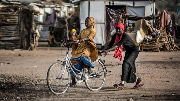 Two girls play while riding a bicycle at the camp. An Islamic State-allied faction has in recent months overrun military bases, seizing equipment and weapons, and forcing tens of thousands of people to flee for their lives. Nigeria’s election commission has been forced to set up special measures for them to vote: in Borno, some 4,00,000 displaced people will vote at 10 centres. Several others have been created in Adamawa. (Luis Tato / AFP)