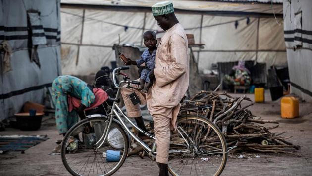 A man carries his son on a bicycle at the camp. The main opposition candidate, Atiku Abubakar, has seized on the insecurity and claimed Buhari has failed in his core duty of keeping Nigerians safe. (Luis Tato / AFP)