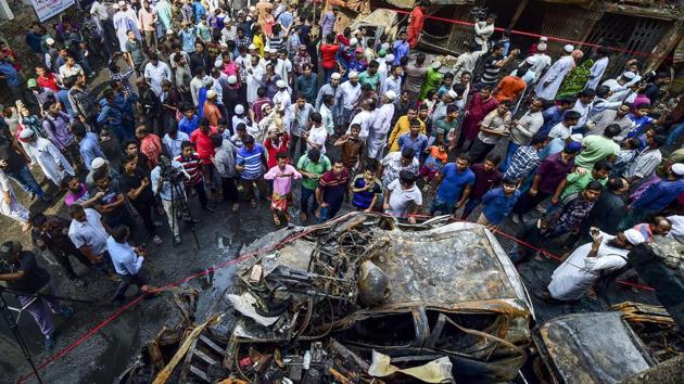 People gather around the wreckage of gutted cars. While the government of Prime Minister Sheikh Hasina touts the garment factories and gleaming office towers in Dhaka’s north side as signs of progress, illegal shops and overcrowding in Chawkbazar, one of the city’s many warren-like southern districts, impeded firefighters’ ability to put out the fire. (Munir Uz Zaman / AFP)