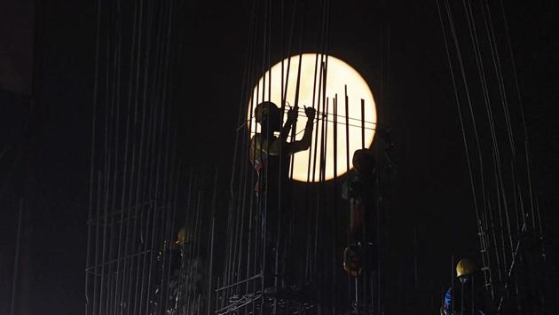 A ‘Super Snow Moon’ rises as construction labourers work at a building site in Kolkata, West Bengal. (Dibyangshu Sarkar / AFP) A ‘Super Snow Moon’ rises as construction labourers work at a building site in Kolkata, West Bengal. (Dibyangshu Sarkar / AFP)