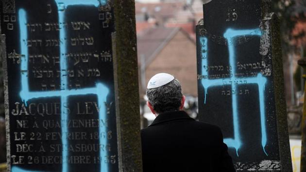 A man walks by graves vandalised with swastikas at the Jewish cemetery in Quatzenheim, on the day of a nationwide marches against a rise in anti-Semitic attacks, close to the border with Germany in the Alsace region. (Frederick Florin / AFP)