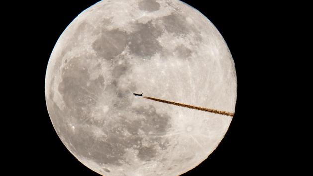 A plane flies past the full moon in Nuremberg, Germany. (Daniel Karmann / dpa / AFP)