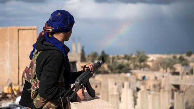 A member of the Syrian Democratic Forces (SDF) stands guard on top of a building, in the frontline Syrian village of Baghuz. (Fadel Senna / AFP)