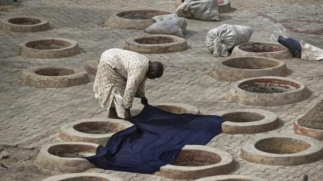 A craftsman lays indigo-dyed cloth to dry over some of the ancient dye pits of Kofar Mata. Although many of the abandoned traditional pits appeared to be choked with debris, Ismailu said they are maintained in case of a revival: “We take care.” (Ben Curtis / AP)
