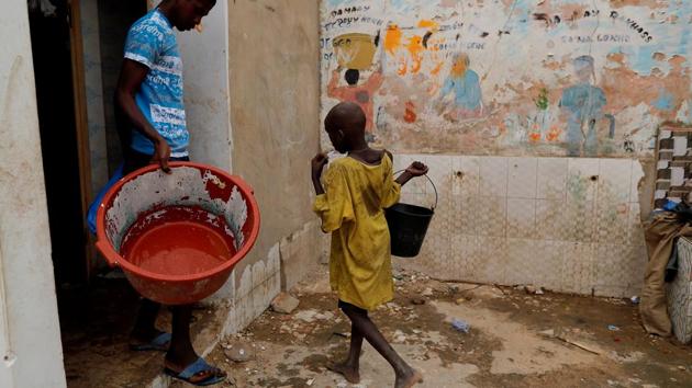Moussa, a talibe, from Futa, carries a bucket of water to take a shower at Maison de la Gare. In recent decades, some rights groups say the talibes have at times been kept by marabouts in dire conditions, forced to beg for money and beaten if they do not come back with enough. There are no safeguards for children who escape and find themselves alone on the streets, they say. (Zohra Bensemra / REUTERS)
