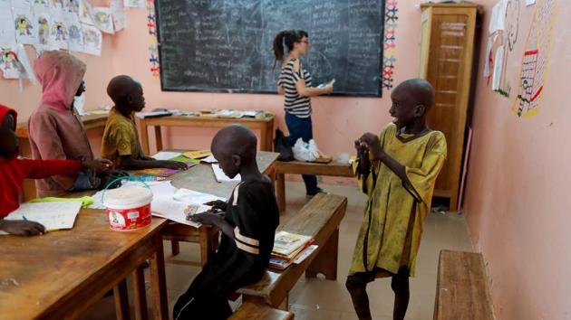 Moussa stands inside a classroom of Maison de la Gare. In Saint-Louis, as in the capital Dakar, groups of children weave through traffic asking for money, wearing shorts and ragged football shirts bearing the names of their millionaire heroes. At Maison de la Gare, talibes can eat a sandwich, shower, wash their clothes and receive first aid assistance. There are opportunities to learn English and play sport. (Zohra Bensemra / REUTERS)