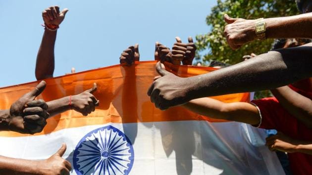 Indian residents raise their thumbs in front of the national flag as they participate in a demonstration to support Indian armed forces in Chennai, following an Indian Air Force (IAF) strike launched on a Jaish-e-Mohammad (JeM) camp at Balakot.(AFP)