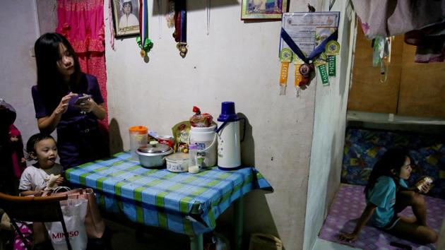 Janice Sarad looks at the television as her sister eats a snack at their home. “There's no money left for me to save. My salary goes to my sister's tuition fee, bills to pay at home, and my fare to go to work. There is nothing left for me,” she said. “When I feel stressed, I try not to dwell on it. I just think about how lucky I am being able to work, and for getting home safely every day.” (Eloisa Lopez / REUTERS)