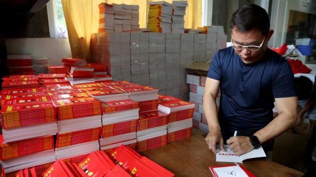 Ferdinand Tan, 53, wealth coach and motivational speaker, signs his books on financial advice in his home in Cainta City. When Tan is not at his speaking engagements, he works from home. His employees, both full-time and part-time, also work from home. (Eloisa Lopez / REUTERS)