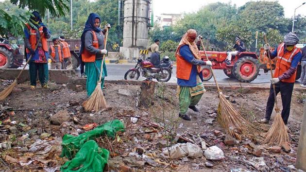 MCG contractual workers cleaning garbage near Huda City Centre fire station on Sunday.(Yogendra Kumar/HT PHOTO)