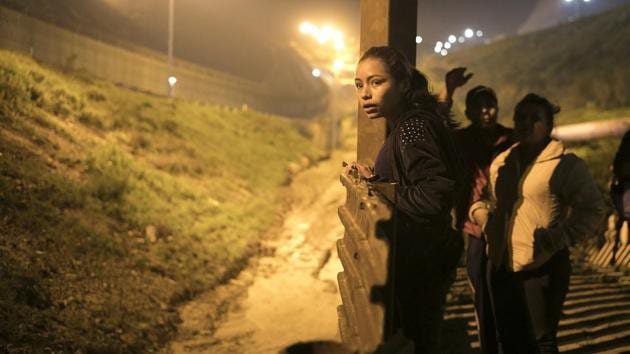 Xiomara Henriquez Ayala peers over the US border fence from Tijuana as Josue Mejia Lucero and his sister Lucero, 25, look on while looking for a way to help Lucero and her son cross undetected. Milagro says they no longer need their father: She’s about to become a parent herself and considers herself something of a mother to Xiomara after being forced to care for her on her own. (Emilio Espejel / AP) Xiomara Henriquez Ayala peers over the US border fence from Tijuana as Josue Mejia Lucero and his sister Lucero, 25, look on while looking for a way to help Lucero and her son cross undetected. Milagro says they no longer need their father: She’s about to become a parent herself and considers herself something of a mother to Xiomara after being forced to care for her on her own. (Emilio Espejel / AP)