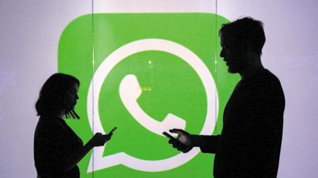 People are seen as silhouettes as they check mobile devices whilst standing against an illuminated wall bearing WhatsApp Inc's logo in this arranged photograph in London, UK.(Bloomberg)