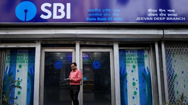 A man checks his mobile phones in front of State Bank of India (SBI) branch in Kolkata.(REUTERS)