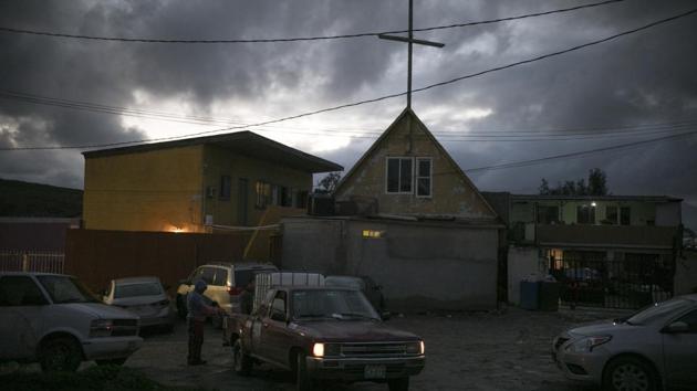 A man stands outside the Agape World Mission shelter, topped with a cross, in Tijuana. The sisters travelled with about two dozen other young people as a kind of subgroup of the caravan, which grew to more than 5,000 people. Once in Tijuana, the group scattered, and some crossed into the United States illegally. Others were detained in Mexico and deported. (Emilio Espejel / AP) A man stands outside the Agape World Mission shelter, topped with a cross, in Tijuana. The sisters travelled with about two dozen other young people as a kind of subgroup of the caravan, which grew to more than 5,000 people. Once in Tijuana, the group scattered, and some crossed into the United States illegally. Others were detained in Mexico and deported. (Emilio Espejel / AP)