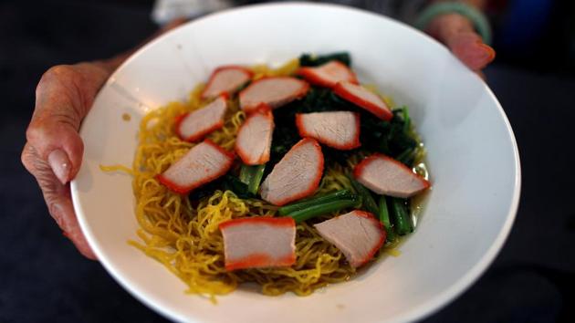 Leong Yuet Meng presents a bowl of wonton noodle soup at her shop. “Before applying for that (UNESCO), I think they have to settle the problems in front of them first. Twenty years down the road when all the older generation pass away, who is going to take over?,” said Alan Choong, a 24-year-old owner of Sino-Japanese fusion food stall Prawnaholic. (Edgar Su / REUTERS)