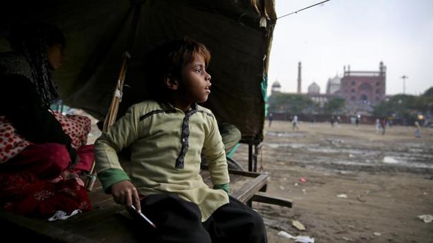 7-year-old Farmaan looks out from his home, set up on a wooden fruit vendor's cart, as it drizzles in New Delhi. Someday, the family says, the 7-year-old will save them. “I’ll fight,” the boy’s mother said when her husband insisted their son start working. She vowed he would stay in school, no matter what. (Altaf Qadri / AP) 