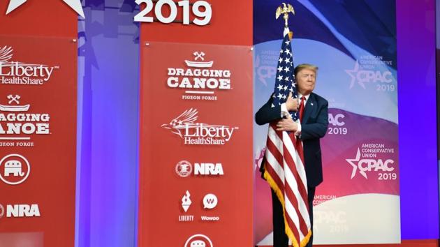 US President Donald Trump hugs the US flag as he arrives to speak at the annual Conservative Political Action Conference (CPAC) in National Harbor, Maryland. (Nicholas Kamm / AFP) 