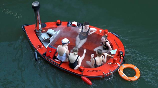 Women sail in a floating electric hot tub on a waterway near the River Thames and Canary Wharf, in London, England. (Peter Nicholls / REUTERS) 