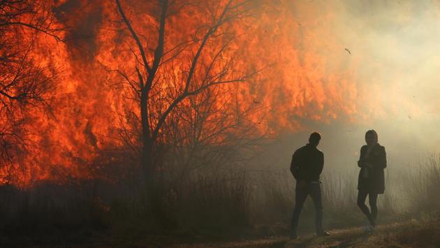 People look at flames of a fire as dry grass and bushes burn near the village of Ivanovka, Crimea. (Alexey Pavlishak / REUTERS) 