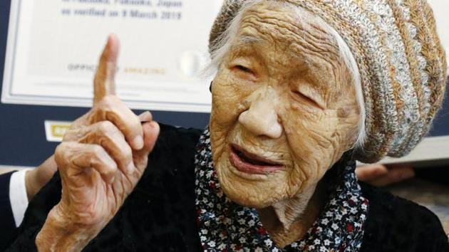 Kane Tanaka, a 116-year-old Japanese woman, gestures after receiving a Guinness World Records certificate, back, at a nursing home where she lives in Fukuoka.(AP)