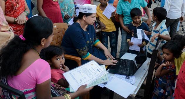 An Aam Aadmi Party volunteers helps parents fill online registration forms in a slum area in Baner on Saturday.(Milind Saurkar/HT Photo)