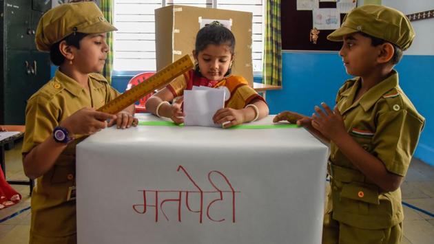 Mock police officers of Abhinav pre primary school keep vigil while a civilian casts her vote. (Sanket Wankhade/HT PHOTO) 