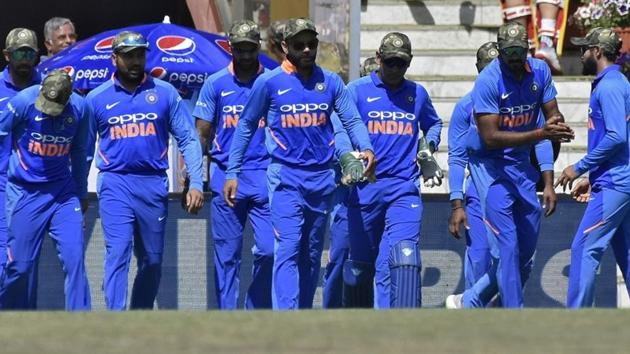 Virat Kohli (C) and his teammates wearing army camouflage-style caps walk onto the field.(REUTERS)