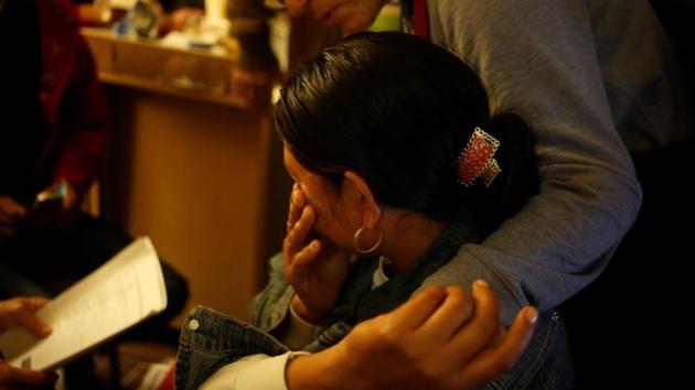 Volunteer Irene Murillo comforts a Guatemalan woman after calls to her brother-in-law back in Central America failed to connect, in a motel room used as an operations office in a motel. Migrants are assigned an immigration court near where they will live. They can wait years for their asylum hearing due to a backlog in cases, according to Reuters data. (Nicole Neri / REUTERS)