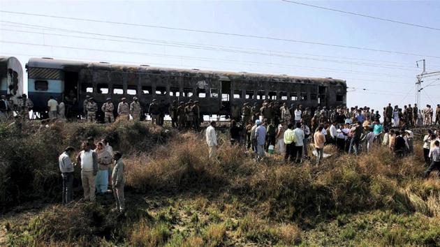 People gathered near the bogies of Samjhuata Express burn after an explosion in Delhi-Atari Samjhauta Express at Dewana village near Panipat on February 19, 2007.(PTI Photo)