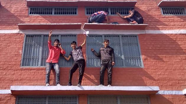 Bhiwani: Youths trying to supply slips for copying at an examination centre in government Senior secondary school in Tosham town of Bhiwani district on Monday.(Manoj Dhaka/HindustanTimes)