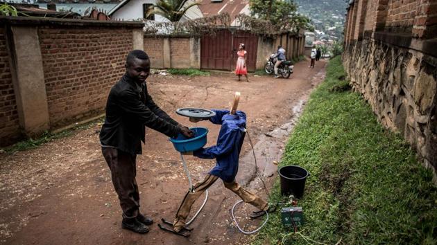 Electrical Engineer Germain Kasereka, demonstrates how a self made automatic hand washing robot works to assist in the fight against Ebola, on a street in Butembo, Democratic Republic of the Congo. The team believe that by the use of an automatic hand washing station, it will help stop people from touching the same tap handles before and after washing their hands. (John Wessels / AFP) Electrical Engineer Germain Kasereka, demonstrates how a self made automatic hand washing robot works to assist in the fight against Ebola, on a street in Butembo, Democratic Republic of the Congo. The team believe that by the use of an automatic hand washing station, it will help stop people from touching the same tap handles before and after washing their hands. (John Wessels / AFP)
