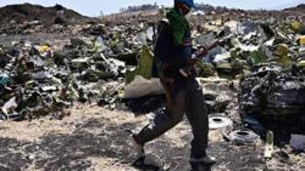 An Oromo man hired to assist forensic investigators walks by a pile of twisted airplane debris at the crash site of an Ethiopian airways operated Boeing 737 MAX aircraft on March 16, 2019 at Hama Quntushele village near Bishoftu in Oromia region. - A French investigation into the March 10 Nairobi-bound Ethiopian Airlines Boeing 737 MAX crash that killed 157 passengers and crew opened on March 15 as US aerospace giant Boeing stopped delivering the top-selling aircraft. (Photo by TONY KARUMBA / AFP)(AFP)