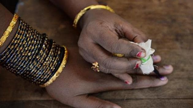 An election official puts indeliable ink on the finger of a voter before she casts her ballot.(AFP File Photo)