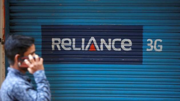 A man speaks on his mobile phone as he walks past a closed shop painted with an advertisement of Reliance Communications in Mumbai on January 29.(REUTERS)