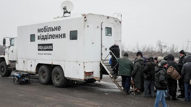 Local residents stand in line to an ATM located in an armoured truck near the front line in Mayorsk. Troops are stationed in trenches outside Zaitseve and government trucks risk rebel fire to bring bread, coal, firewood and other goods along a dirt road. Employees from the state-run Oschadbank travel by armoured truck to a nearby checkpoint, to allow residents on both sides of the conflict to withdraw money. (Gleb Garanich / REUTERS) Local residents stand in line to an ATM located in an armoured truck near the front line in Mayorsk. Troops are stationed in trenches outside Zaitseve and government trucks risk rebel fire to bring bread, coal, firewood and other goods along a dirt road. Employees from the state-run Oschadbank travel by armoured truck to a nearby checkpoint, to allow residents on both sides of the conflict to withdraw money. (Gleb Garanich / REUTERS)