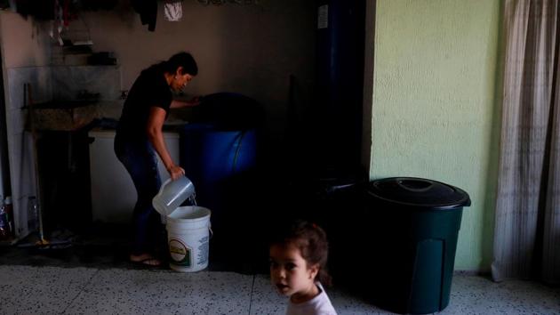 Yuneisy Flores, a 31-year-old homemaker whose family live on the fourth floor, washes her dishes in cartons and strains the water to remove the leftovers of food. She then uses the liquid to flush the toilet. She bathes her 3-year-old daughter in a sink to recycle the water. (Carlos Jasso / REUTERS) 
