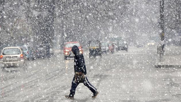 A man seen crossing a road during a rare March spell of snowfall, in Srinagar, Jammu and Kashmir. (Waseem Andrabi / HT Photo) 