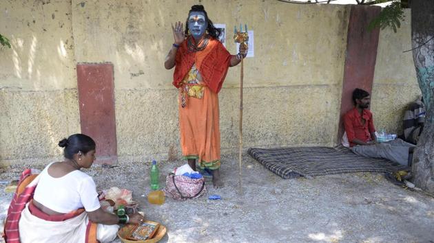 An artist dressed as the Hindu deity Shiva poses on a roadside in Hyderabad, Telangana. (Noah Seelam / AFP) 