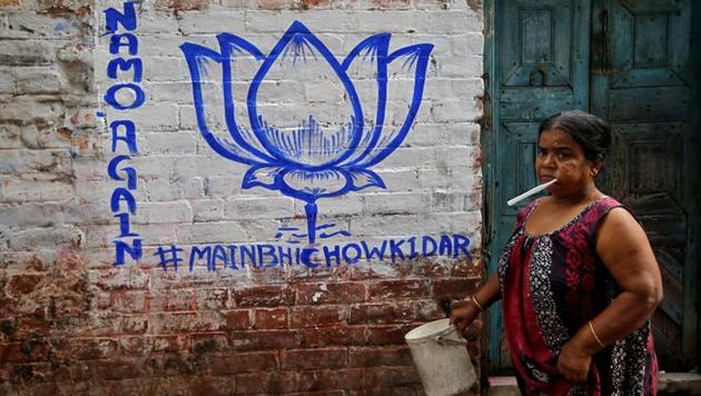 A woman walks past a wall painted with the election symbol of the ruling Bharatiya Janata Party (BJP) in an alley at a residential area in Kolkata, West Bengal. (Rupak De Chowdhuri / REUTERS) 
