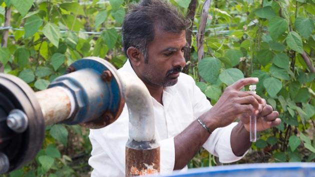 Murali testing the quality of water at his water pump. WaterAid India works with local NGOs and trains farmers like Murali to test drinking water quality by providing pH scale test cards and water testing chemicals. These tests are usually done twice a year – pre and post monsoons. (WaterAid / Rohit Kumar)