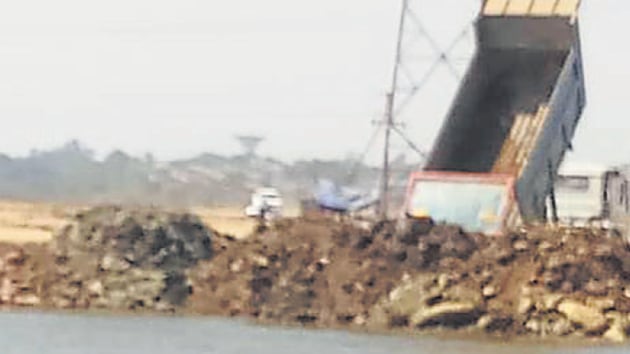 Debris dumping in Bhendkhal in Uran wetlands is slowly leading to reclamation of two water bodies. The image was sent to the state mangrove committee by a panel member.(HT Photo) Debris dumping in Bhendkhal in Uran wetlands is slowly leading to reclamation of two water bodies. The image was sent to the state mangrove committee by a panel member.(HT Photo)