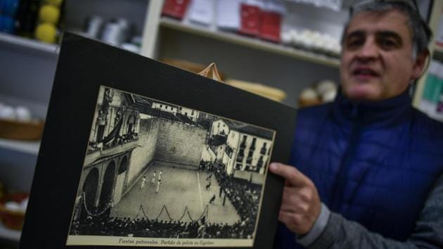 Javier Bariain shows an old photograph of a Basque Ball match, at his store in Pamplona, northern Spain. Pelota Vasca was traditionally played in the village square facing a church, whose facade offered a perfect wall for players to hit the ball. (Alvaro Barrientos / AP) Javier Bariain shows an old photograph of a Basque Ball match, at his store in Pamplona, northern Spain. Pelota Vasca was traditionally played in the village square facing a church, whose facade offered a perfect wall for players to hit the ball. (Alvaro Barrientos / AP)