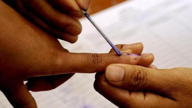 A polling official marks a voter with indelible ink prior to casting a ballot inside a polling station at Bungthuam in Mizoram.(AFP File Photo)