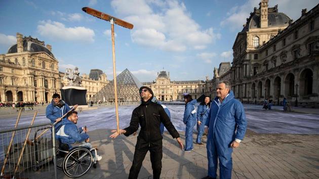 French contemporary artist and photographer Jean Rene (C), aka JR, poses with volunteers during preparation works of his installation in the main courtyard Cour Napoleon of the Louvre Museum. Over the next few days, JR will create a huge collage with the help of 400 volunteers to celebrate its 30th birthday by revealing “the Secret of the Grand Pyramid”. (Thomas Samson / AFP) French contemporary artist and photographer Jean Rene (C), aka JR, poses with volunteers during preparation works of his installation in the main courtyard Cour Napoleon of the Louvre Museum. Over the next few days, JR will create a huge collage with the help of 400 volunteers to celebrate its 30th birthday by revealing “the Secret of the Grand Pyramid”. (Thomas Samson / AFP)