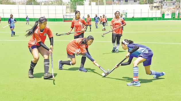 Super XI Girls Academy (blue) in action against Subhadra Nursery Bhosale Public International School’s B-team during the first edition of Moti John hockey tournament at Dhyan Chand hockey stadium on Friday.(HT PHOTO)