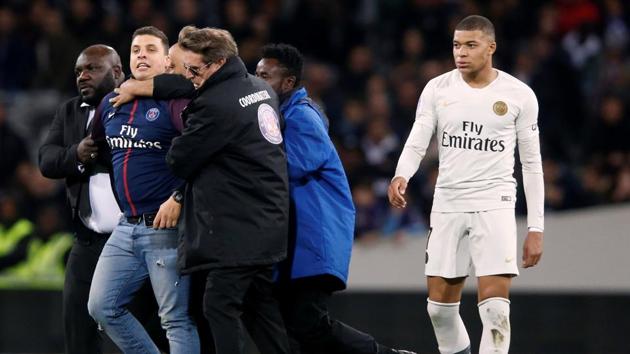 Paris St Germain's Kylian Mbappe looks on as a pitch invader is apprehended by stewards.(Reuters)